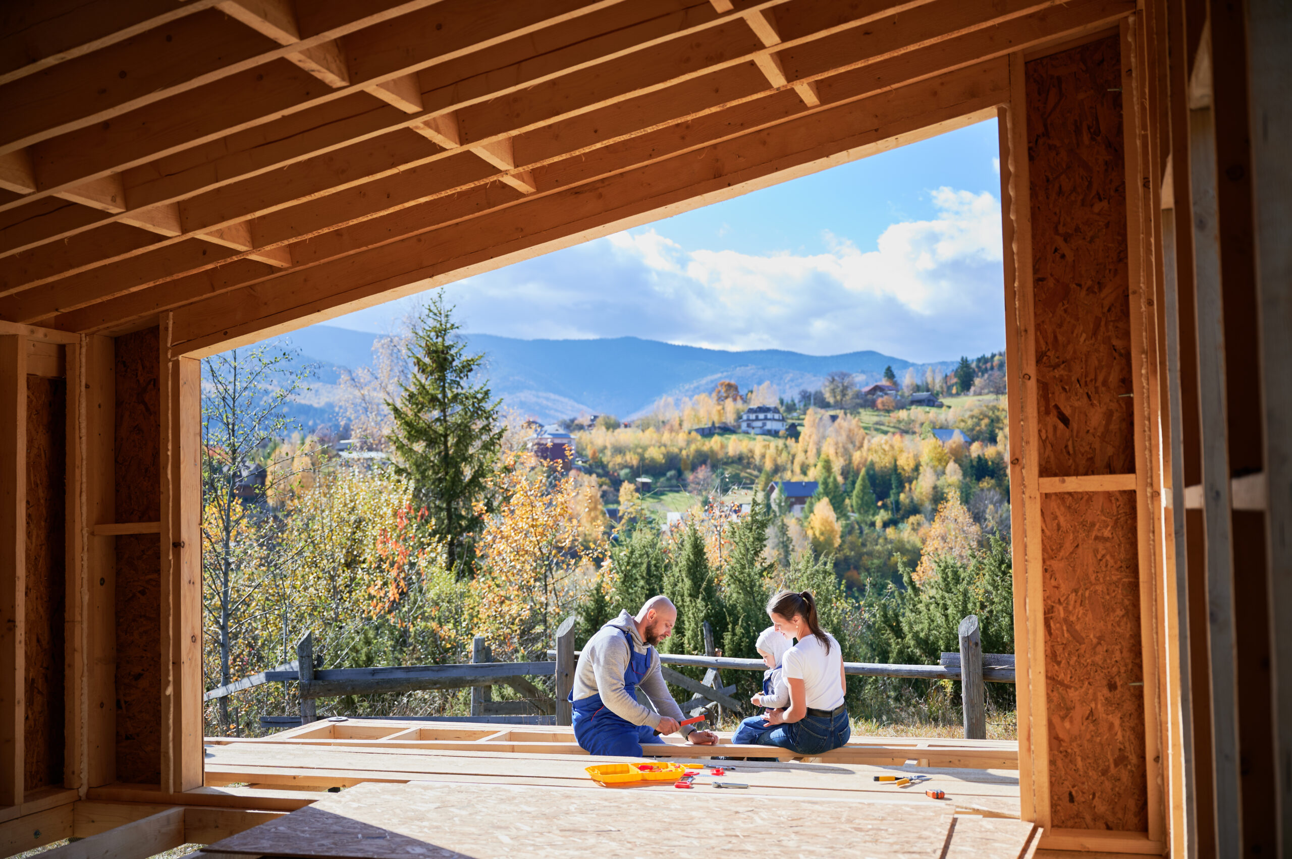 Father, mother and son building wooden frame house.